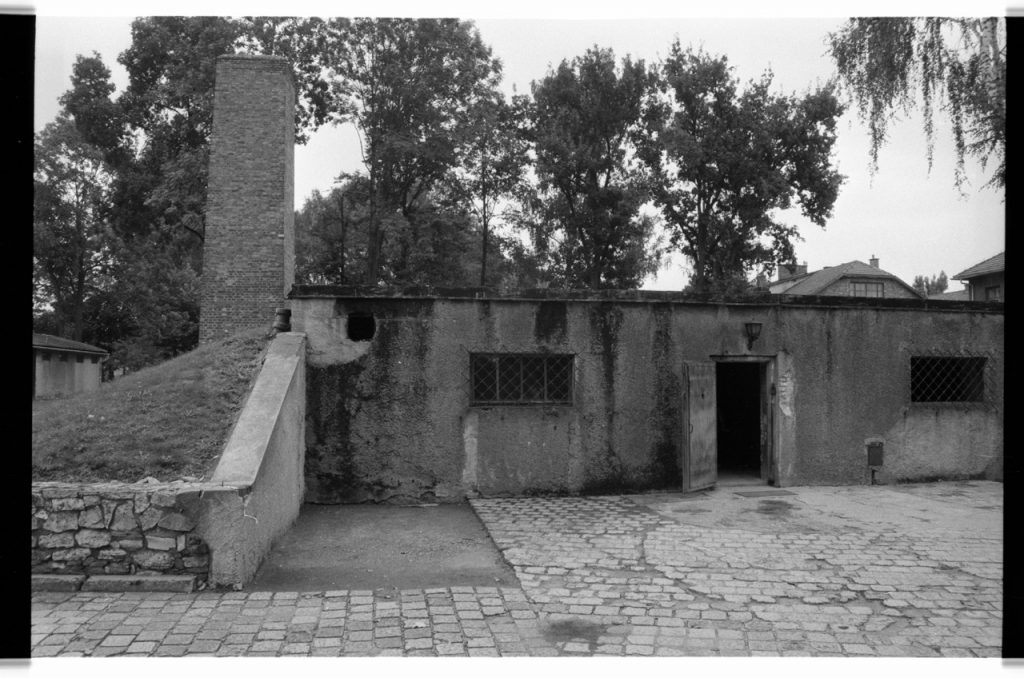B/W photo of front entrance to crematorium. Floors and buildings are all brick with a smoke stack. Nikon D70 Film Camera 2004 - Negative Scan from Nikon COOLSCAN V ED 2008
