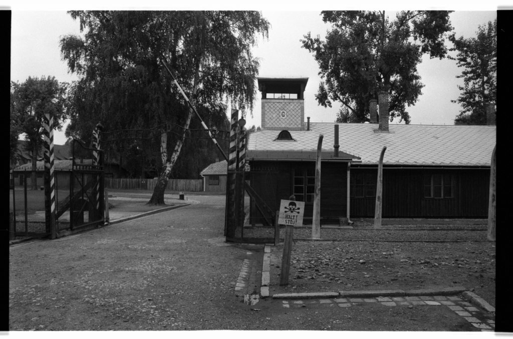 B/W photo of a gatehouse at Auschwitz. Small building with gates and fences. Nikon D70 Film Camera 2004 - Negative Scan from Nikon COOLSCAN V ED 2008