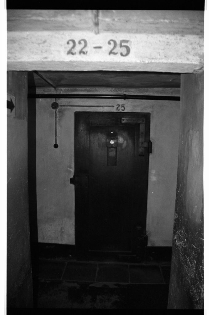 B/W photo of flowers laid by a firing squad area.  Nikon D70 Film Camera 2004 - Negative Scan from Nikon COOLSCAN V ED 2008