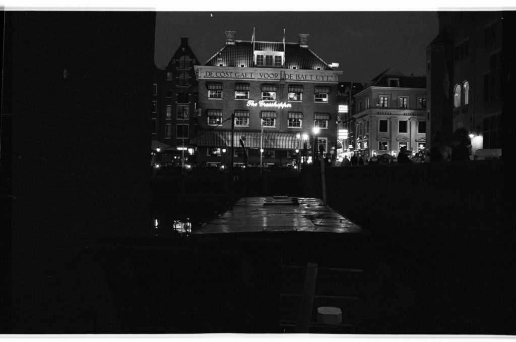 B/W photo of the Grasshopper at night. Neon sign and lights highlighting the building. Nikon D70 Film Camera 2004 - Negative Scan from Nikon COOLSCAN V ED 2008